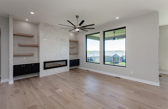 unfurnished living room with recessed lighting, light wood finished floors, and a high end fireplace