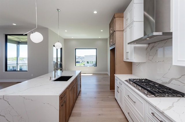 kitchen with stainless steel appliances, a wealth of natural light, a sink, and wall chimney exhaust hood