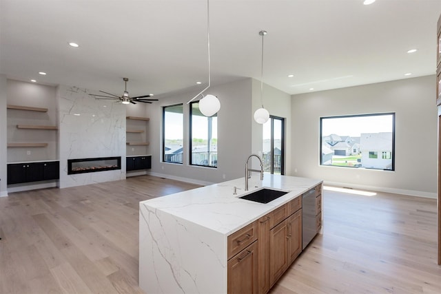 kitchen with stainless steel dishwasher, a sink, light wood finished floors, and open floor plan
