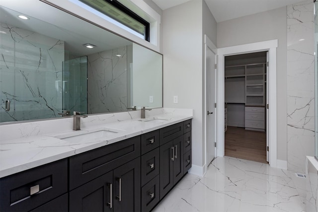 full bath featuring a sink, a marble finish shower, a spacious closet, and marble finish floor