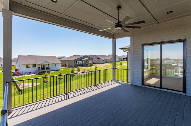 wooden terrace featuring a yard, a ceiling fan, and a residential view