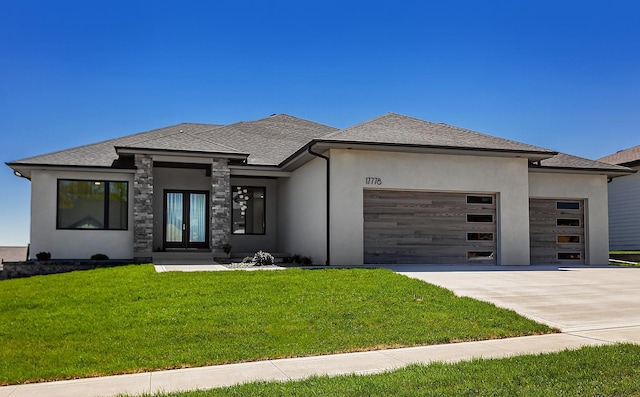 prairie-style home featuring a garage, french doors, a front yard, and concrete driveway