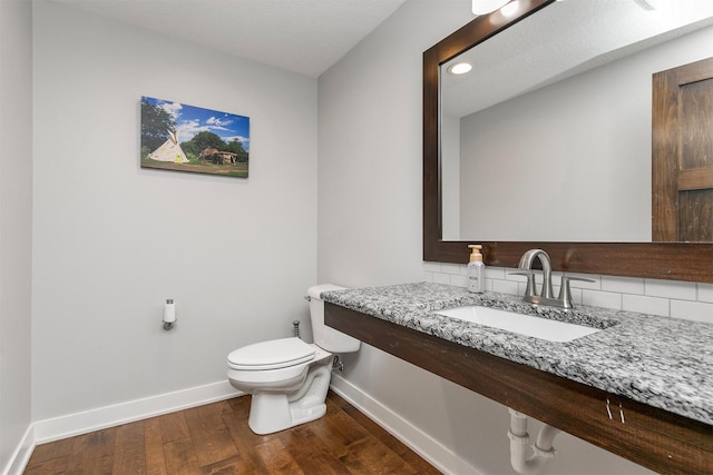 188 Bridgewood Dr, West Des Moines, IA 50266 - bathroom featuring a sink, toilet, baseboards, decorative backsplash, and wood finished floors