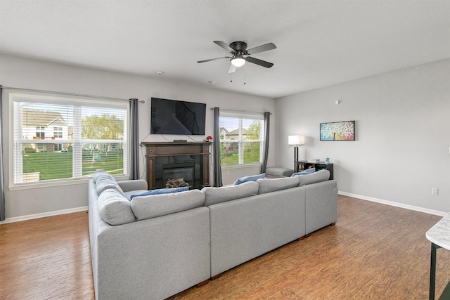 188 Bridgewood Dr, West Des Moines, IA 50266 - living area featuring a glass covered fireplace, baseboards, a ceiling fan, and wood finished floors