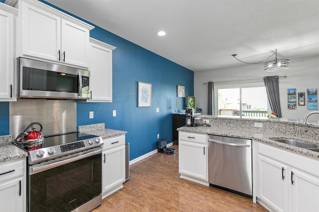 188 Bridgewood Dr, West Des Moines, IA 50266 - kitchen featuring white cabinets, light stone countertops, a sink, light wood-style flooring, and stainless steel appliances
