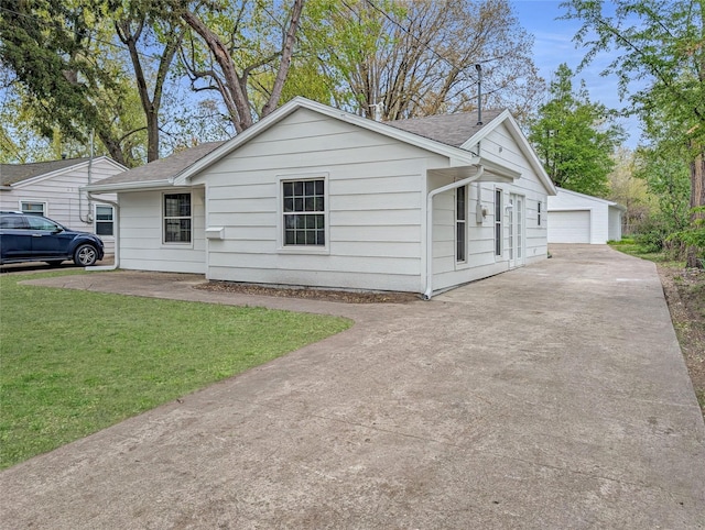 view of front of property with roof with shingles, an outbuilding, a front yard, and a detached garage