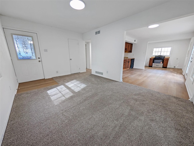 unfurnished living room featuring baseboards, light carpet, and visible vents