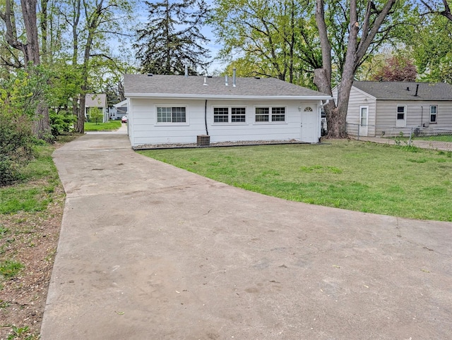 view of front of property with concrete driveway, fence, and a front lawn