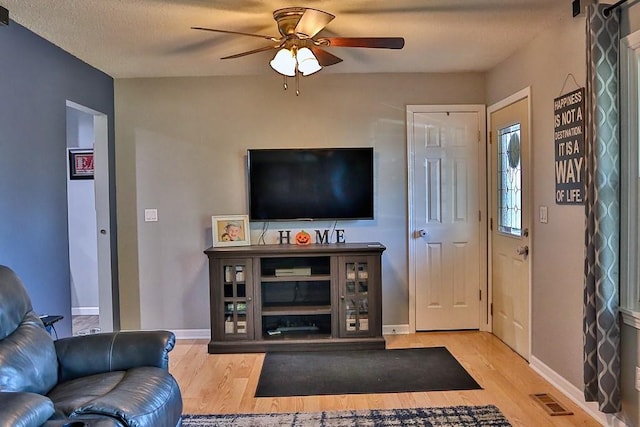 living room with visible vents, a ceiling fan, baseboards, and wood finished floors