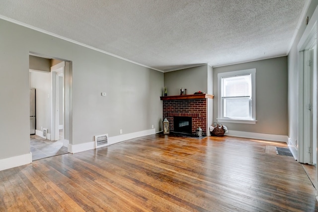 unfurnished living room with visible vents, a brick fireplace, crown molding, and hardwood / wood-style flooring