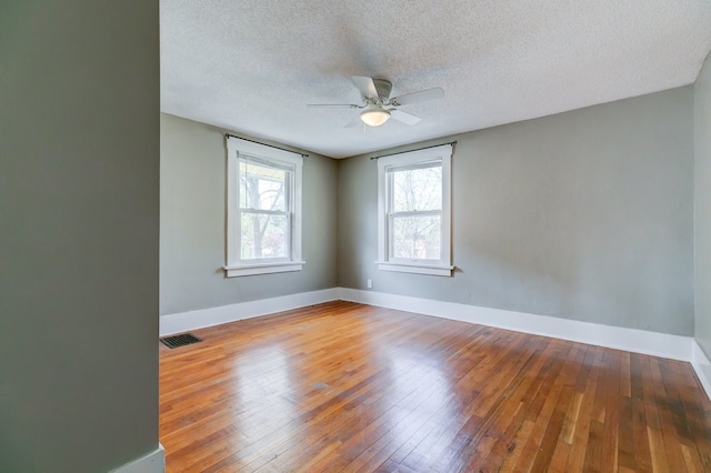 unfurnished room with a ceiling fan, baseboards, visible vents, and hardwood / wood-style floors
