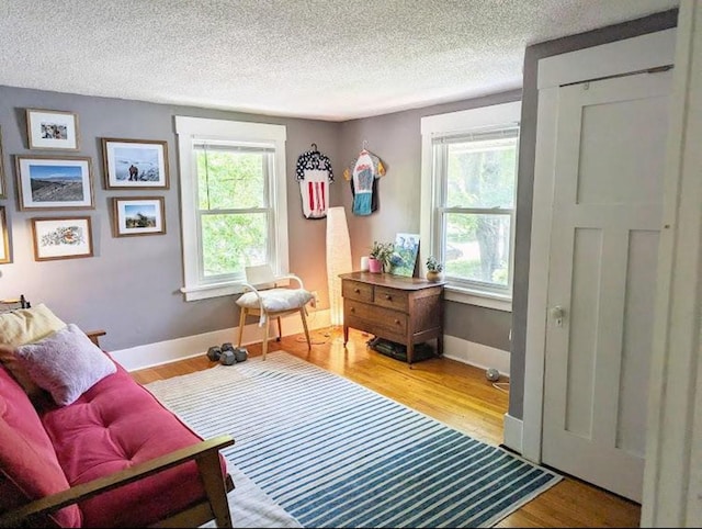 living area with baseboards, a textured ceiling, and wood finished floors