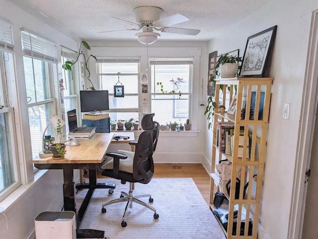 home office featuring baseboards, ceiling fan, wood finished floors, and a wealth of natural light
