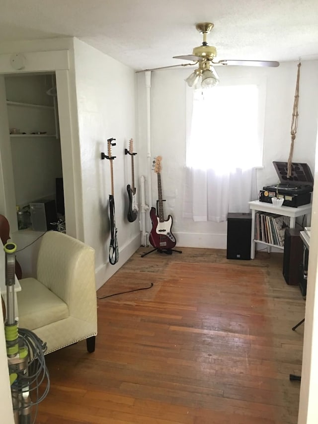 interior space featuring wood-type flooring, ceiling fan, and baseboards