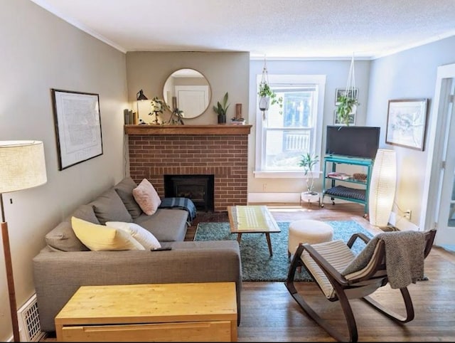 living area featuring visible vents, crown molding, a brick fireplace, and wood finished floors