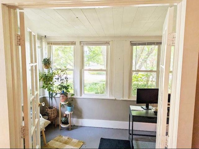 sunroom featuring baseboards and concrete floors