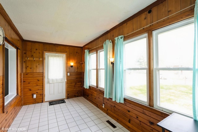 interior space with wooden walls, a textured ceiling, and a wealth of natural light