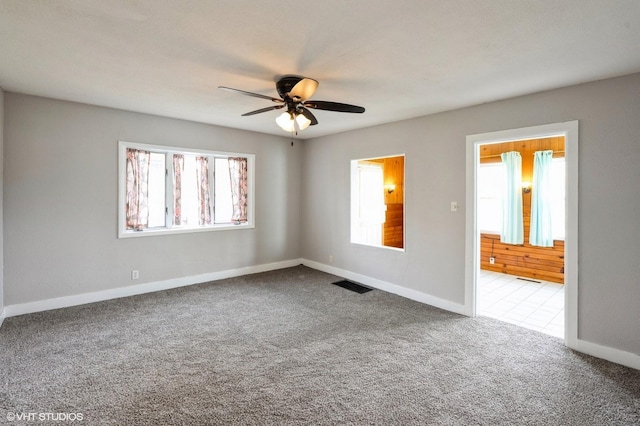 carpeted spare room with baseboards, a ceiling fan, and visible vents