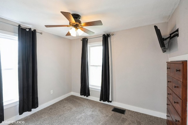 empty room with visible vents, carpet flooring, baseboards, and ceiling fan