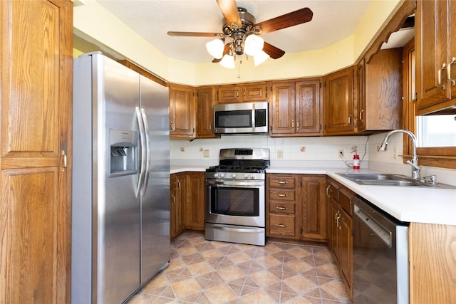 kitchen featuring brown cabinetry, a sink, ceiling fan, and stainless steel appliances