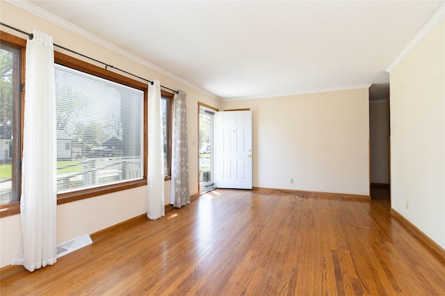 empty room with crown molding, visible vents, a healthy amount of sunlight, and wood finished floors