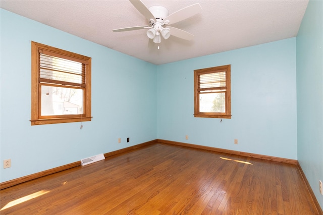 spare room featuring baseboards, a ceiling fan, wood finished floors, and visible vents