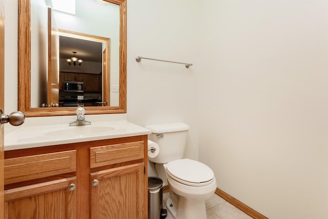 half bath featuring vanity, baseboards, tile patterned floors, and toilet