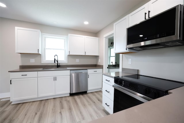 kitchen with stainless steel appliances, a sink, white cabinets, light wood-style floors, and recessed lighting