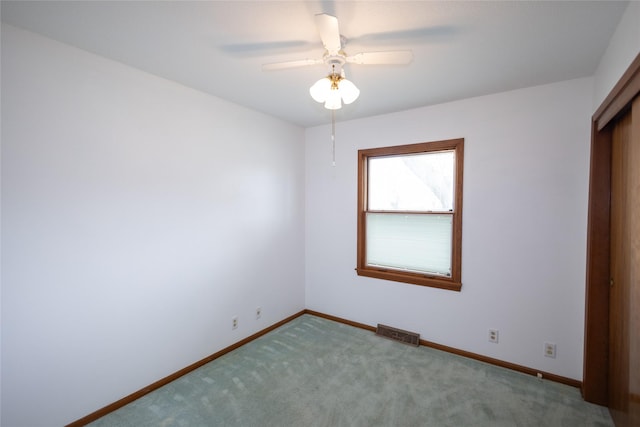 carpeted spare room with baseboards, a ceiling fan, and visible vents