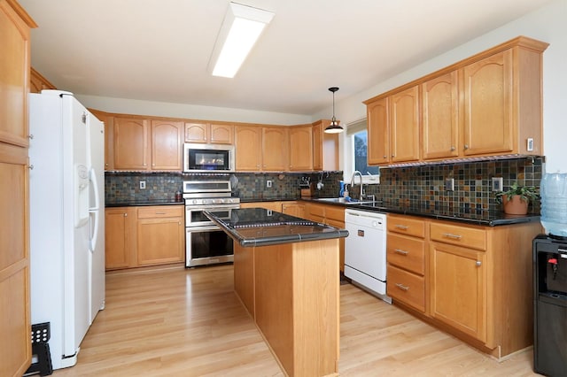 kitchen featuring dark countertops, appliances with stainless steel finishes, a sink, and light wood-type flooring
