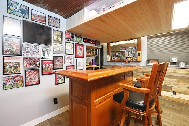 bar featuring wooden ceiling, baseboards, indoor bar, and dark wood-type flooring