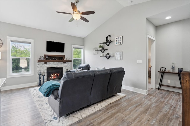 living room with light wood-style floors, a ceiling fan, plenty of natural light, and vaulted ceiling