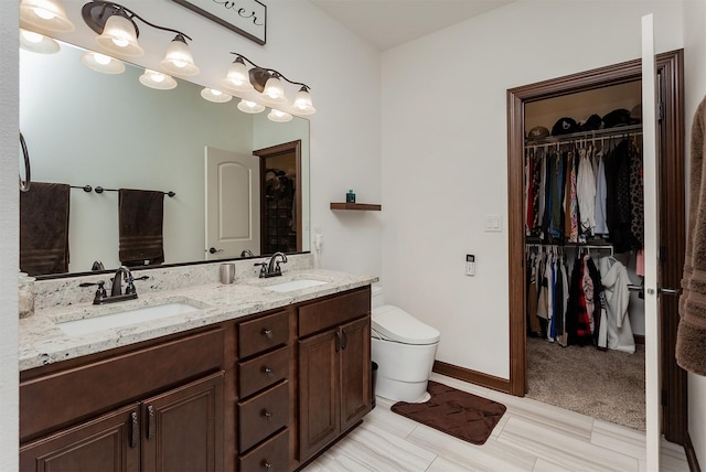 218 34th St SE, Altoona, IA 50009 - bathroom with double vanity, a spacious closet, toilet, and baseboards