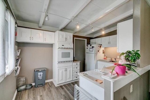 4132 69th St, Urbandale, IA 50322 - kitchen with white appliances, rail lighting, light wood-style flooring, white cabinetry, and beamed ceiling