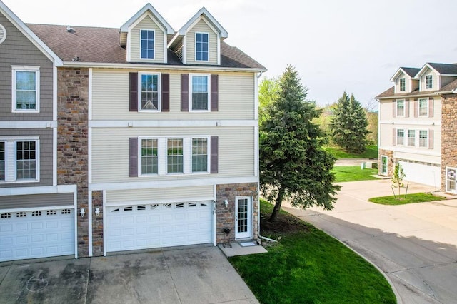 townhome / multi-family property featuring a garage, driveway, and stone siding
