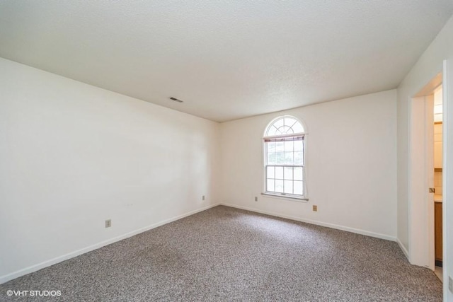 spare room featuring baseboards, visible vents, and carpet