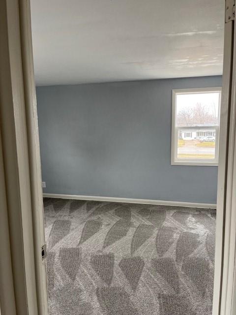 unfurnished room with baseboards and carpet