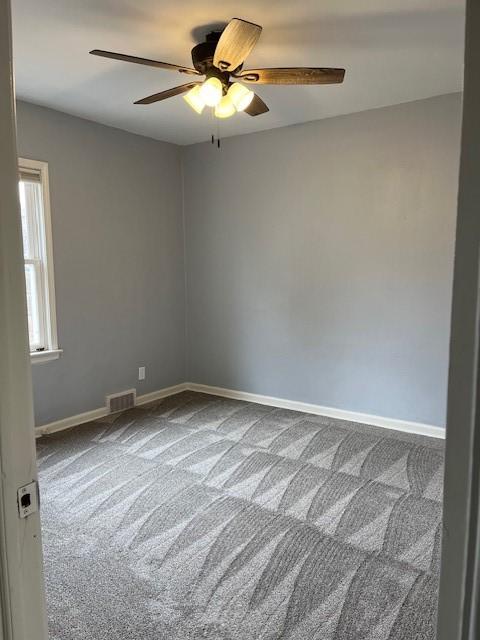 empty room with a ceiling fan, baseboards, visible vents, and carpet