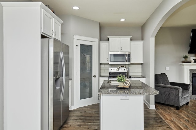 1009 NW Orchard Dr, Ankeny, IA 50023 - kitchen with arched walkways, white cabinetry, appliances with stainless steel finishes, and a fireplace