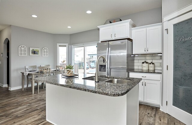 1009 NW Orchard Dr, Ankeny, IA 50023 - kitchen featuring dark wood-style flooring, stainless steel refrigerator with ice dispenser, arched walkways, a sink, and white cabinetry