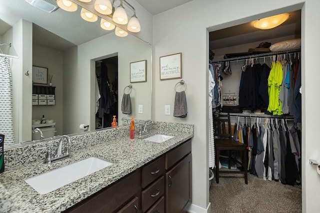 bathroom with double vanity, a sink, and a spacious closet