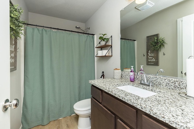 full bath featuring toilet, visible vents, wood finished floors, and vanity
