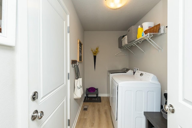 laundry area featuring laundry area, washer and clothes dryer, light wood finished floors, and baseboards