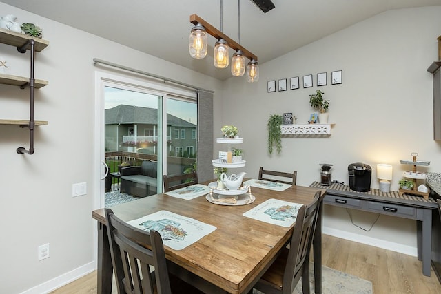 dining room featuring light wood-style floors, baseboards, and vaulted ceiling