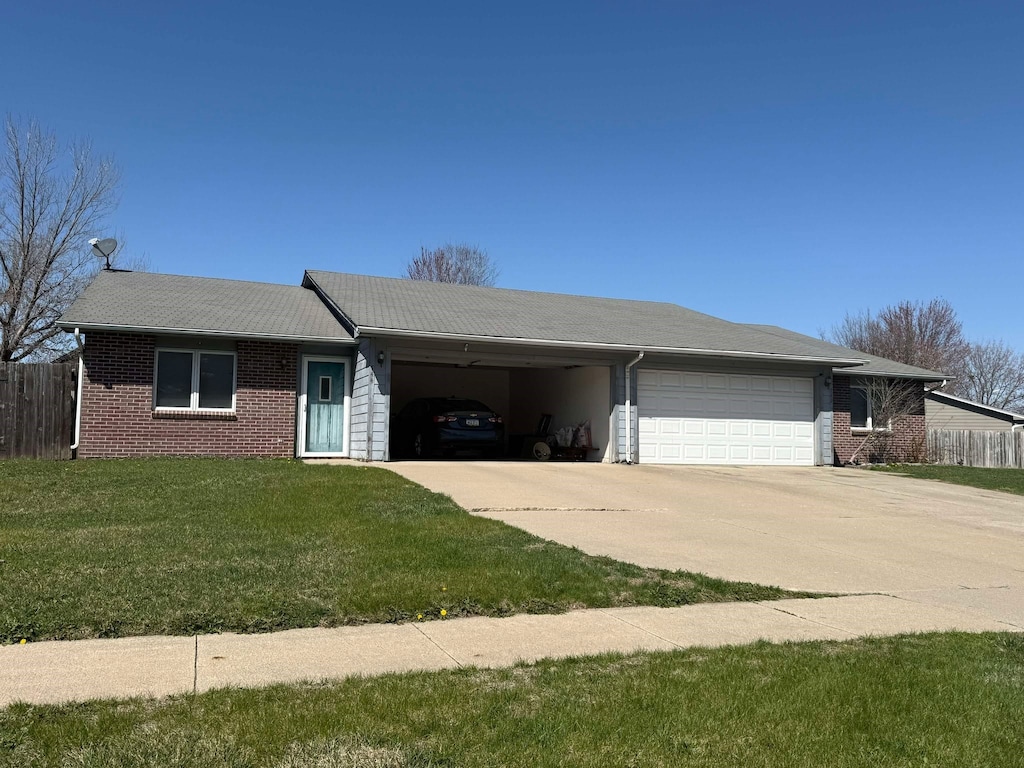 ranch-style house with fence, an attached garage, driveway, and a front lawn