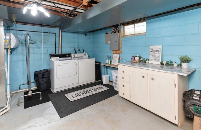 washroom with electric panel, cabinet space, and washer and clothes dryer