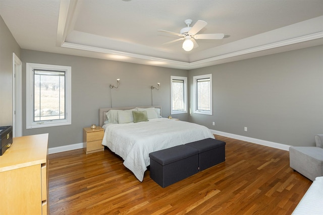 bedroom with multiple windows, a tray ceiling, and wood finished floors
