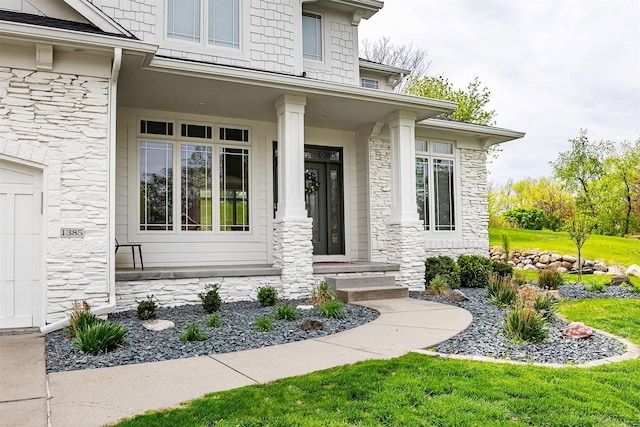 view of exterior entry featuring covered porch and stone siding