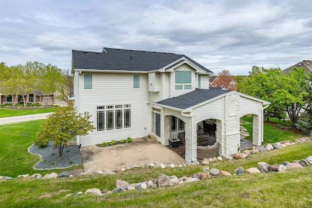 rear view of property with a shingled roof, a yard, and a patio area