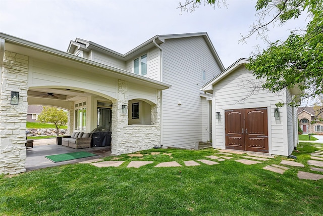 back of property with a lawn and stone siding